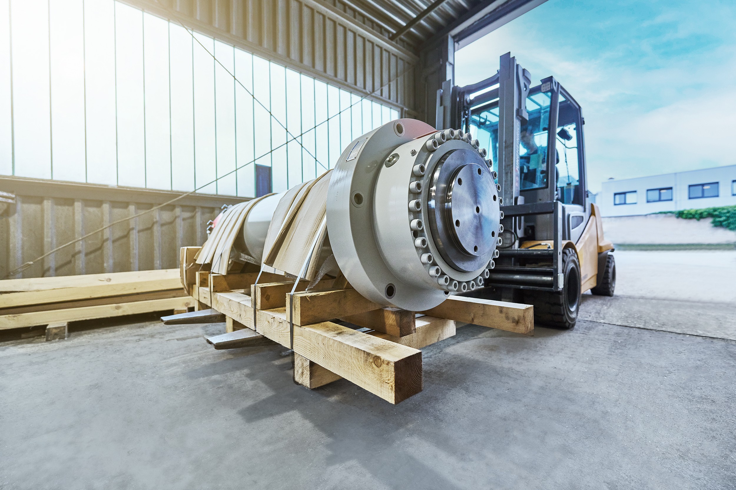 Ein Gabelstapler f&auml;hrt einen gro&szlig;en innovativen und speziell angefertigten Hydraulikzylinder in die ACONA-Halle